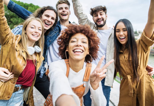 A multiracial group of young adults smiling and cheering.