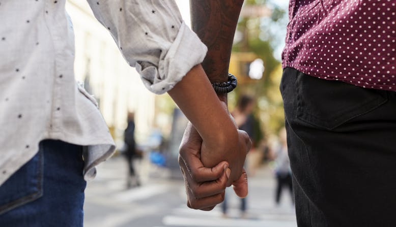 A young interracial couple holding hands in the city.