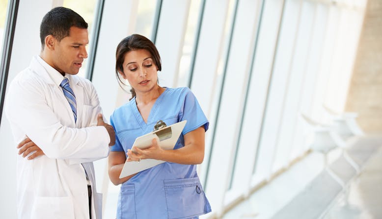 Two doctors in a hallway looking at a patient chart.
