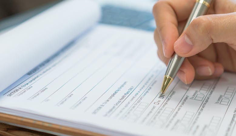 Close-up of a hand filling out an insurance form.