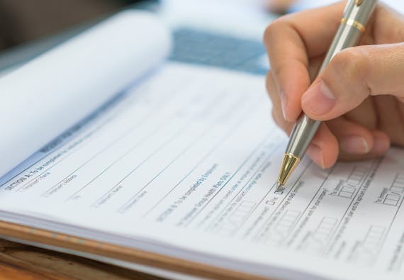 Close-up of a hand filling out an insurance form.