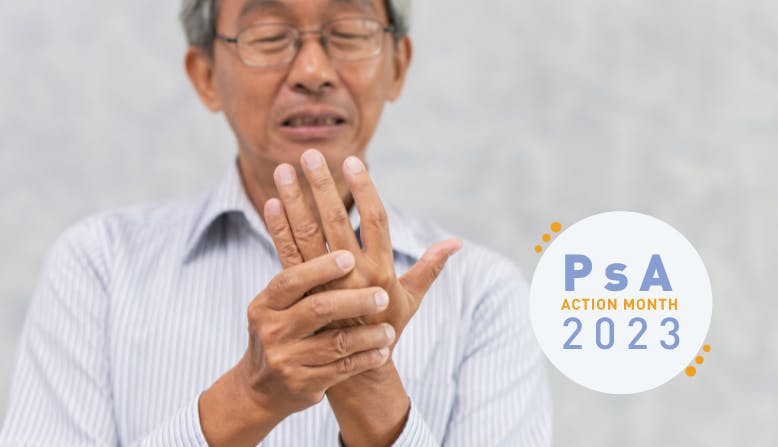 An elderly Asian man holds his hand in pain. PsA Action Month 2023 graphic overlaid.