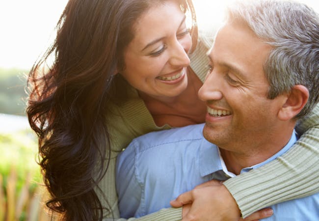 A couple embrace outside in the sun.