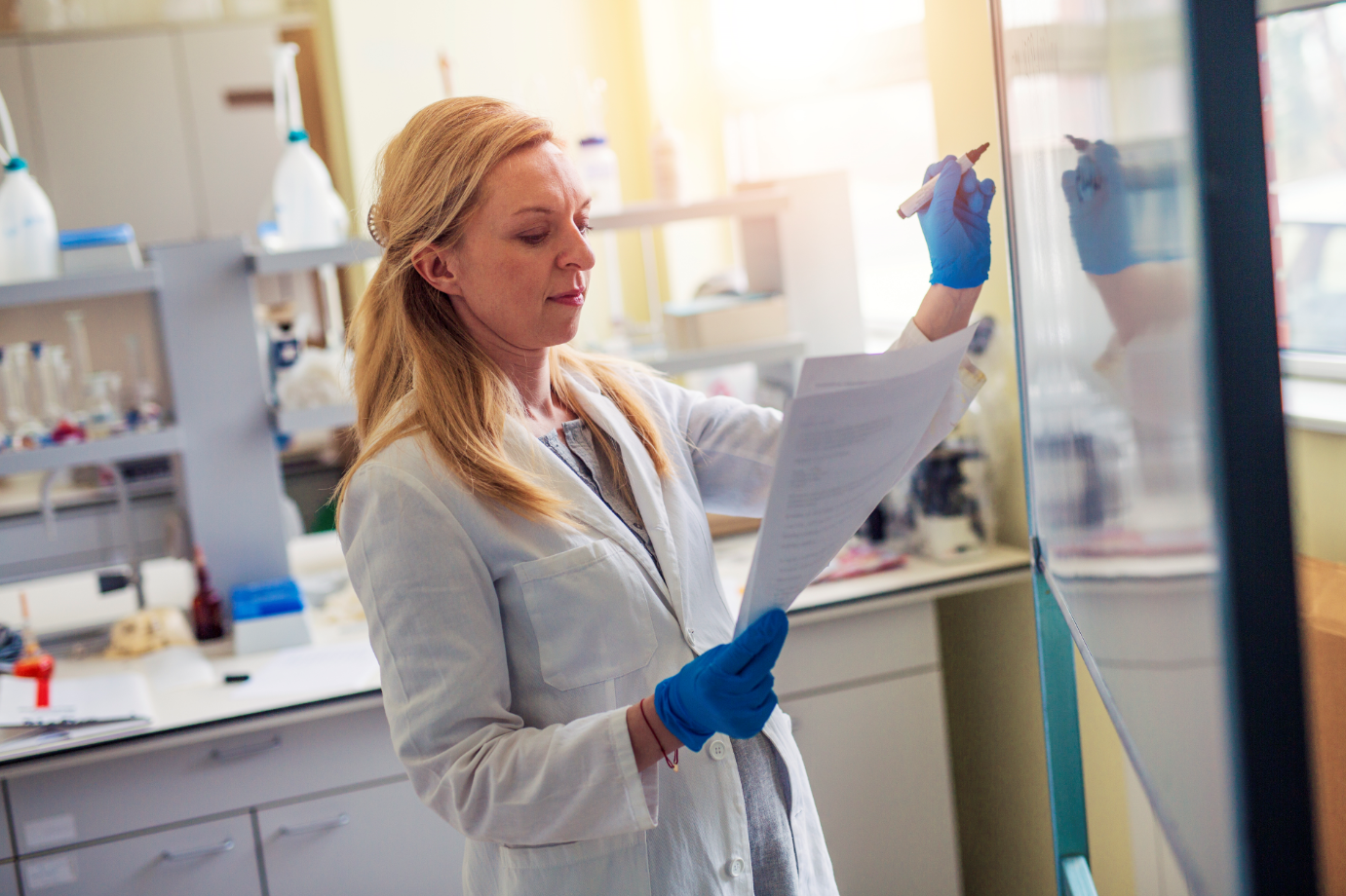 A woman writes on a whiteboard in a lab