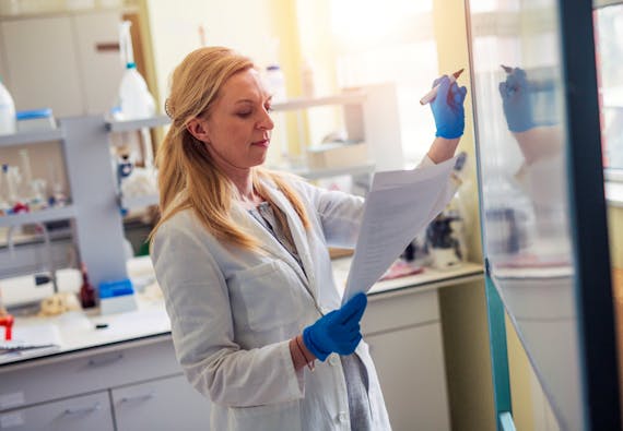 A woman writes on a whiteboard in a lab