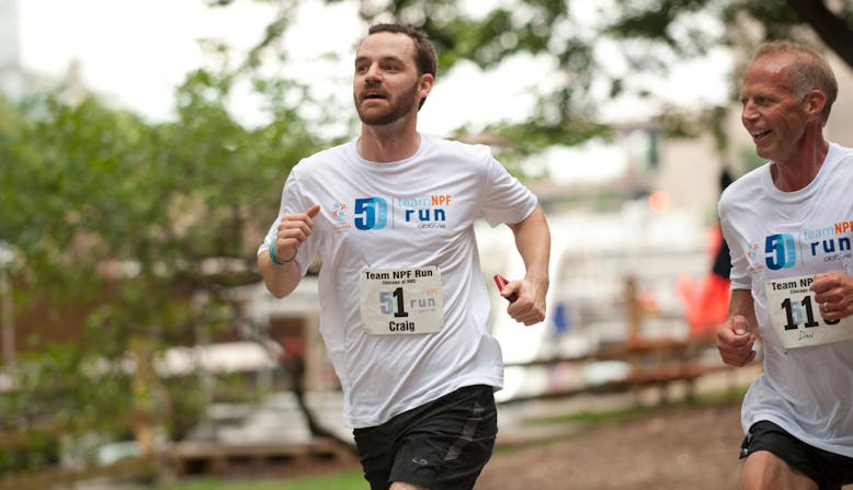 Two runners in Team NPF shirts running and smiling.