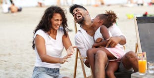 A family laughing together on the beach. 