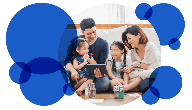 A family sits on the ground and looks at a tablet.