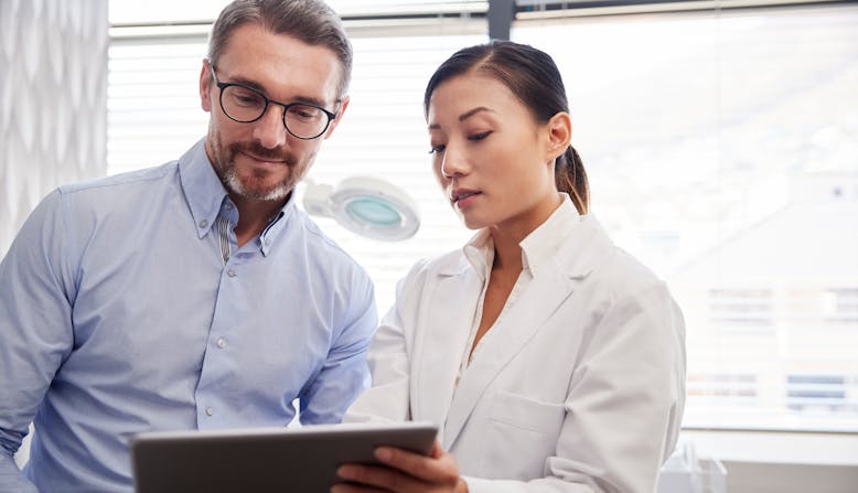 A female health care professional looking at an iPad with a male health care professional.