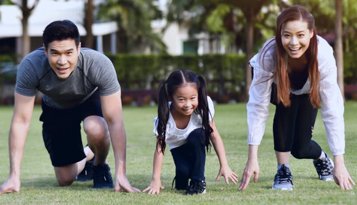 A family crouches down preparing to race each other in a park.