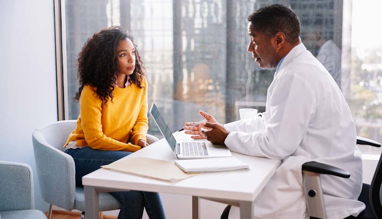 A male doctor discusses with a female patient in an office.