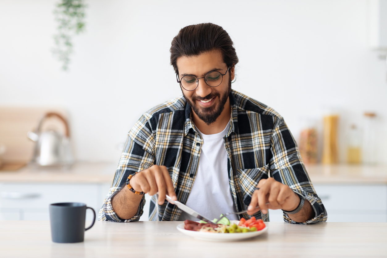 A man sitting and eating in a kitchen.
