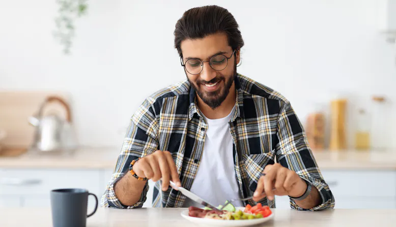 A man sitting and eating in a kitchen.
