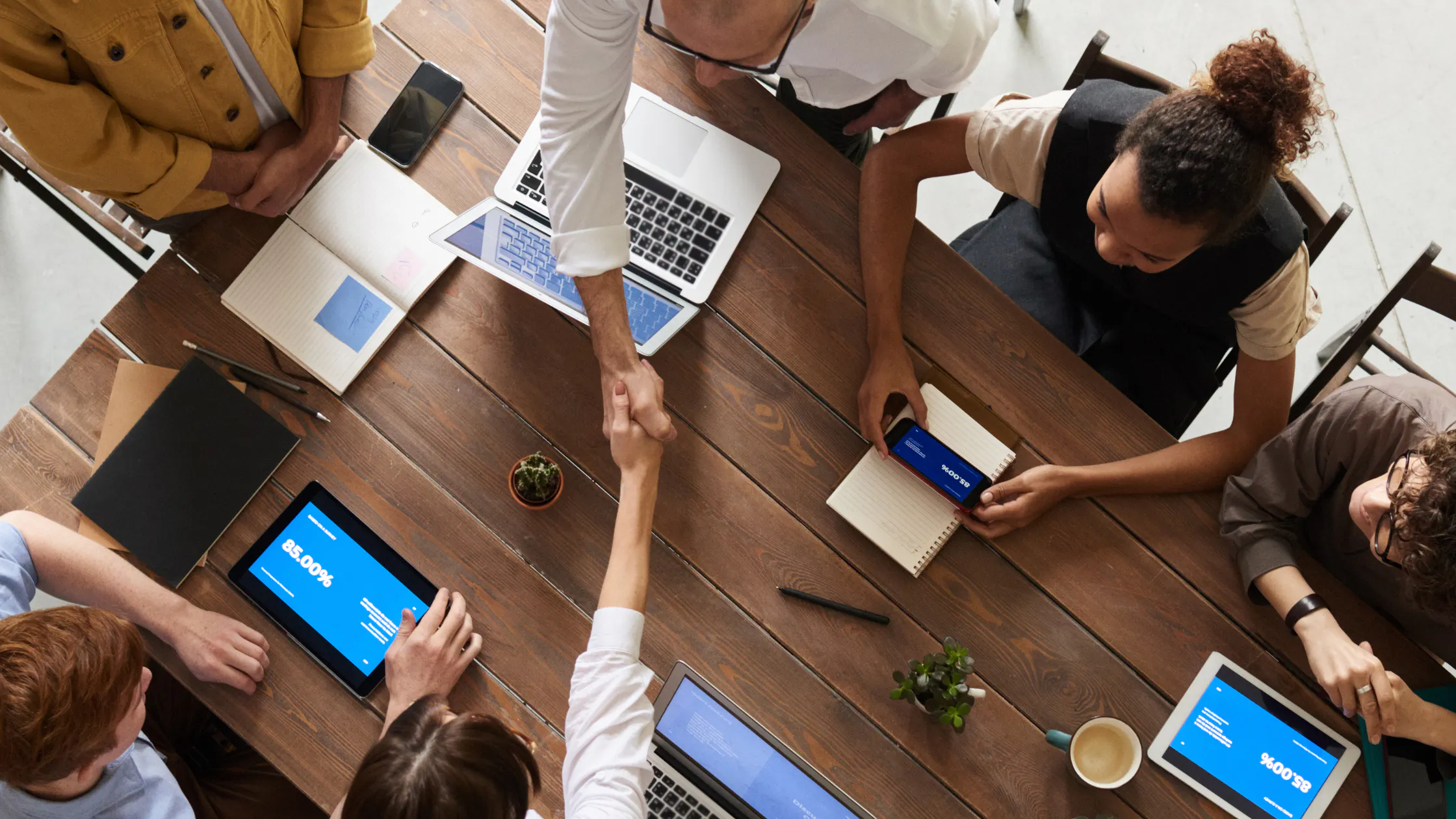 People shaking hands over a table in a meeting
