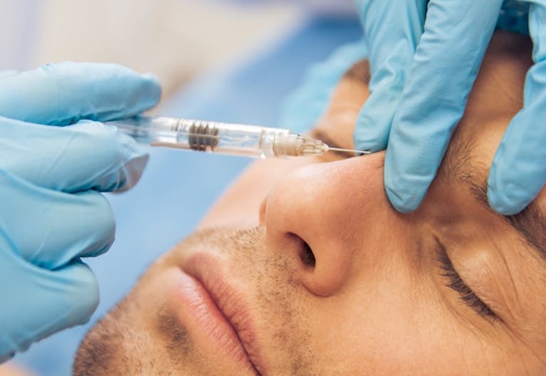 Man receiving botox injection in frown line