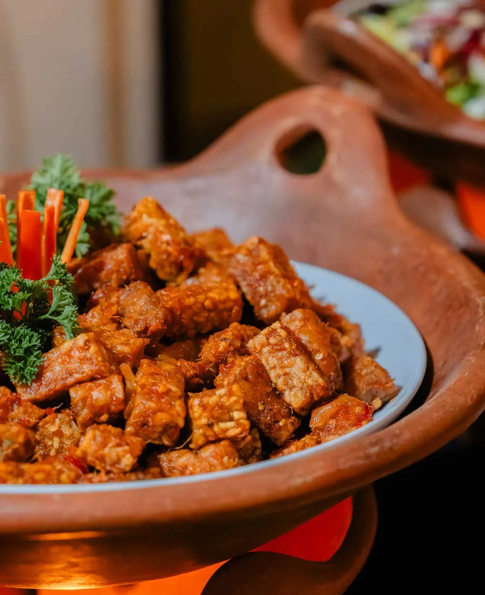 Crispy fried tempeh coated in spicy sambal sauce, at a beachfront Bali restaurant