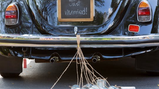 Image of a VW beetle with Jut married sign and tin cans dragging on the ground