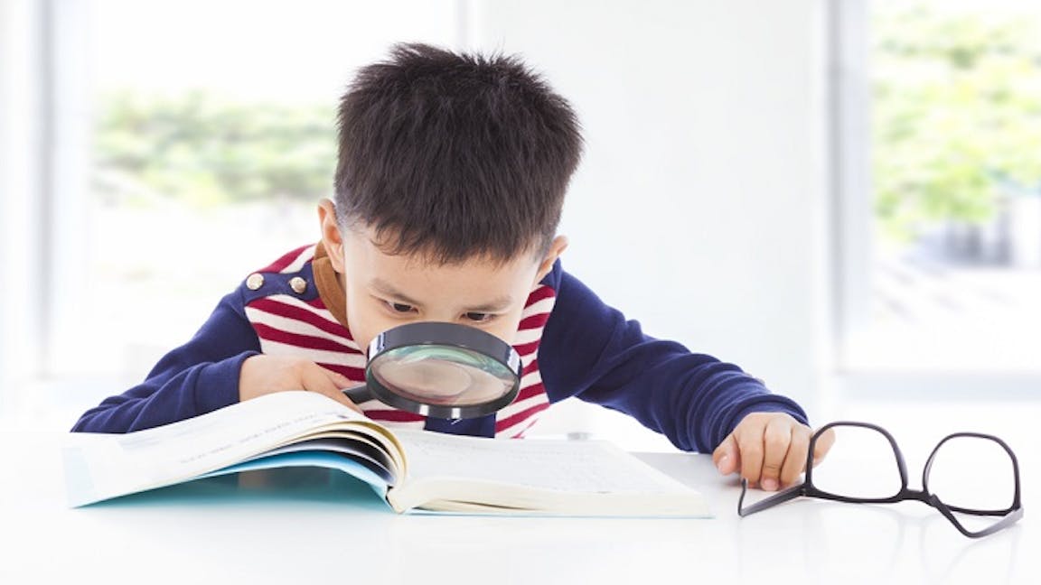 Boy examining text with magnifying glass