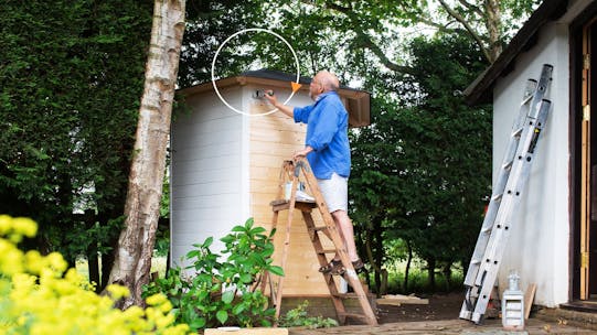 Pensioner painting a shed