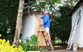 Pensioner painting a shed