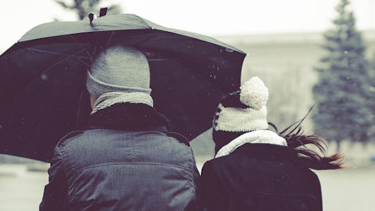 Man and woman walking under umbrella