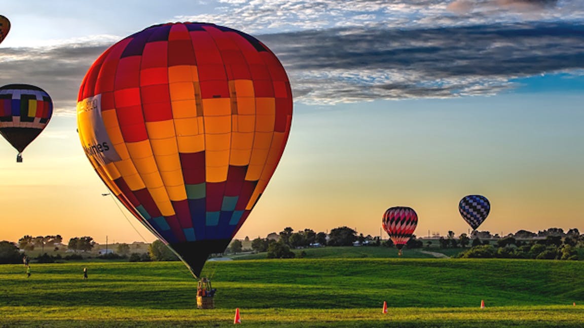Photo of five hot air balloons floating into distance