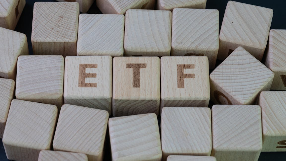ETF, Exchange Traded Fund concept, cube wooden block with alphabet building the word ETF at the center on dark blackboard background.