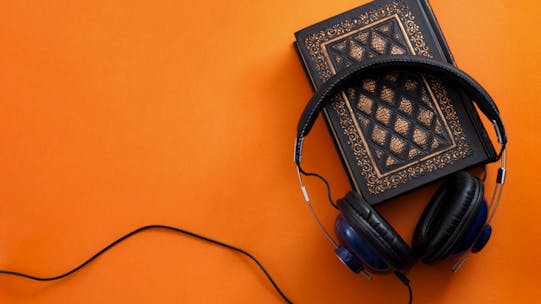 Headphones and a vintage book against an orange background