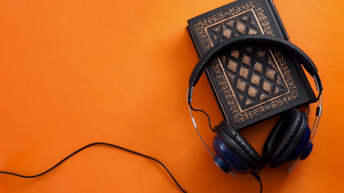 Headphones and a vintage book against an orange background
