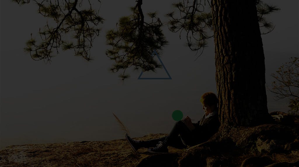 Young man writing in a notebook under the tree