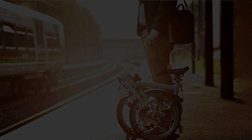 Man waiting at the train platform with a foldable bicycle