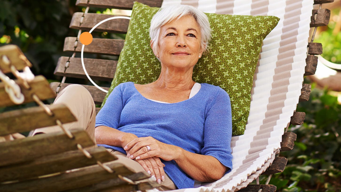 Senior woman lying in a hammock out in the garden