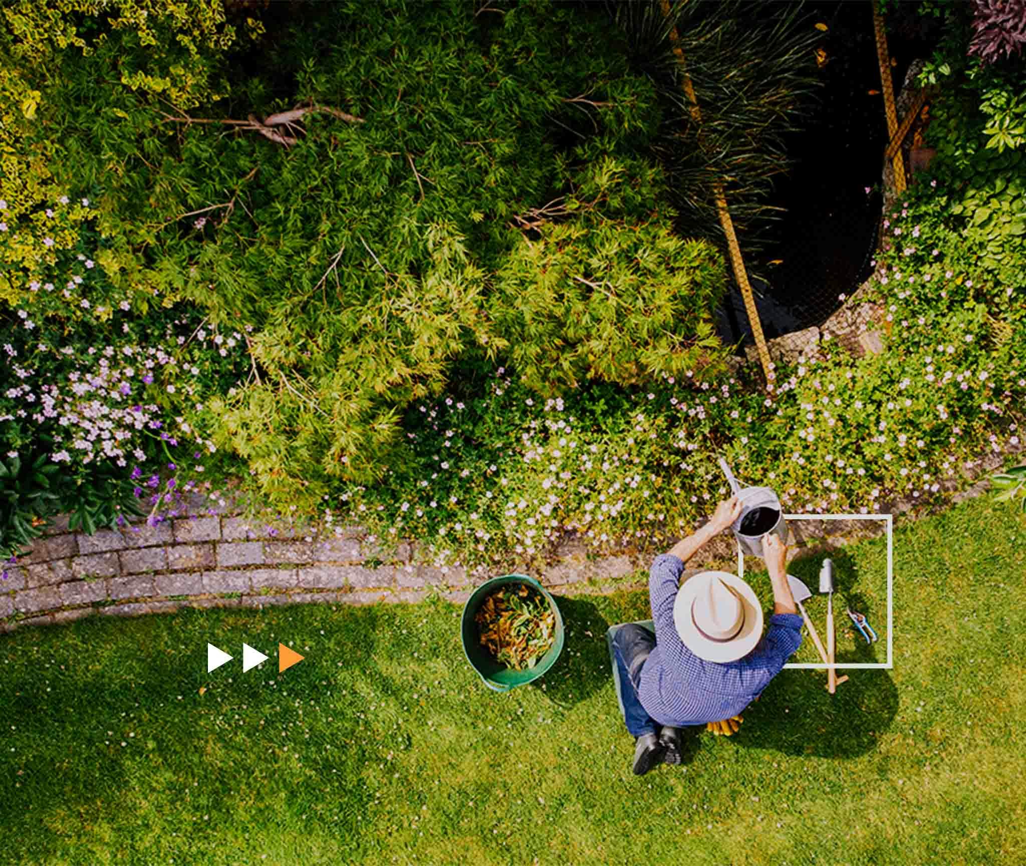 man watering a flowerbed on his garden lawn