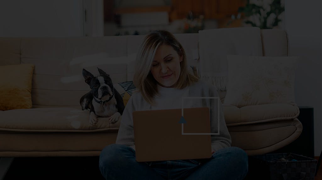 Woman sitting in the living room floor navigating on her laptop