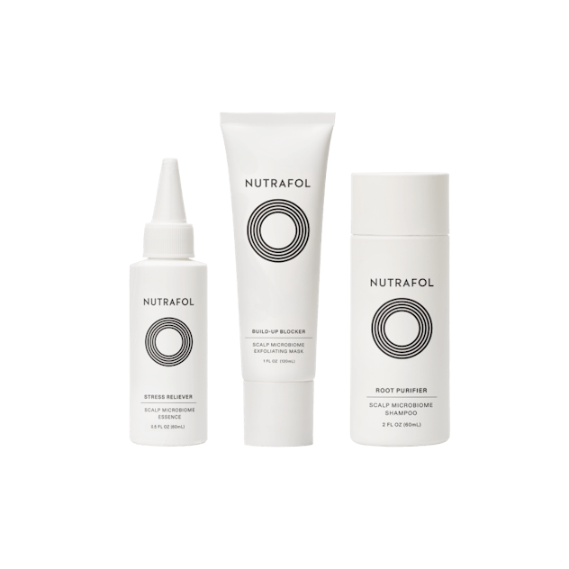 White bottles of Nutrafol Exfoliating Mask, Root Purifier Shampoo, and Stress Reliever Essence.