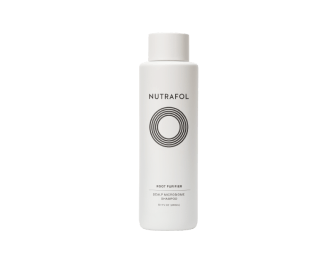 White bottle of Nutrafol Root Purifier Scalp Microbiome Shampoo with white, foamy shampoo behind the bottle.|Root Purifier Scalp Shampoo