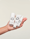 Hand holding three white scalp care bottles.
