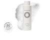 White bottle of Nutrafol Root Purifier Scalp Microbiome Shampoo with white, foamy shampoo behind the bottle.