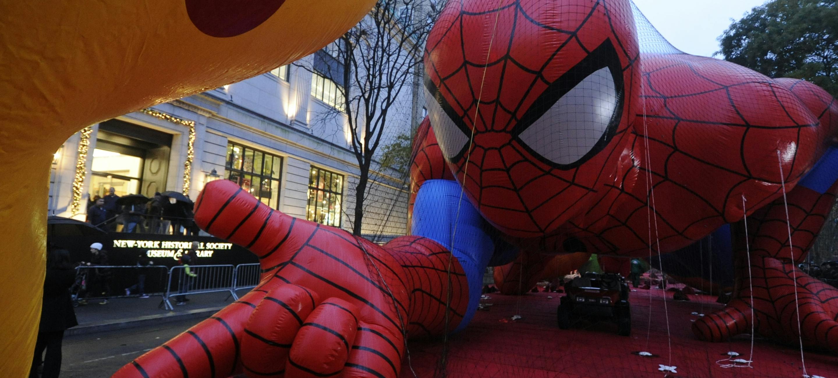 a balloon in the shape of Spider-Man is inflated in front of the New-York Historical Society building before the Macy's Thanksgiving Day Parade