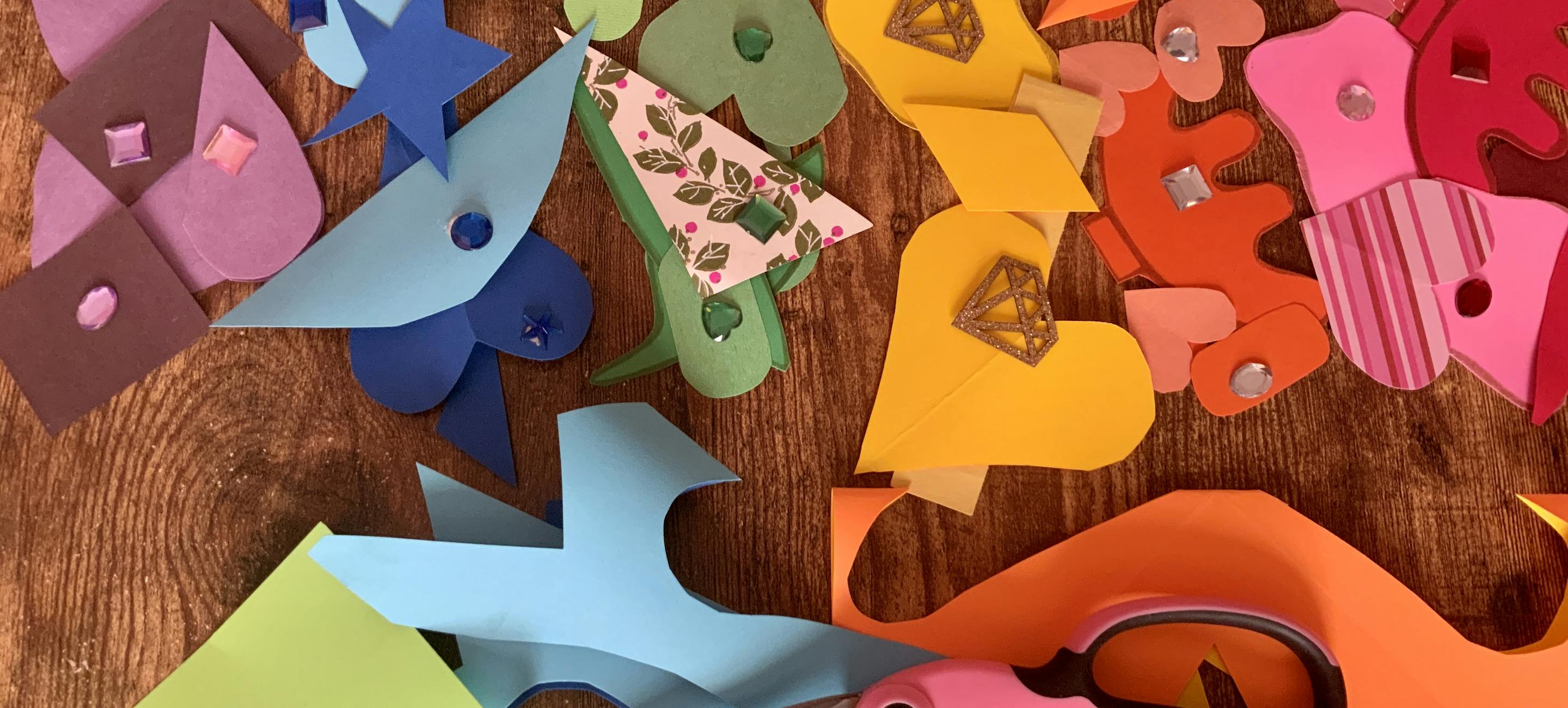 colorful shapes cut out and laid on a table with a pair of scissors nearby