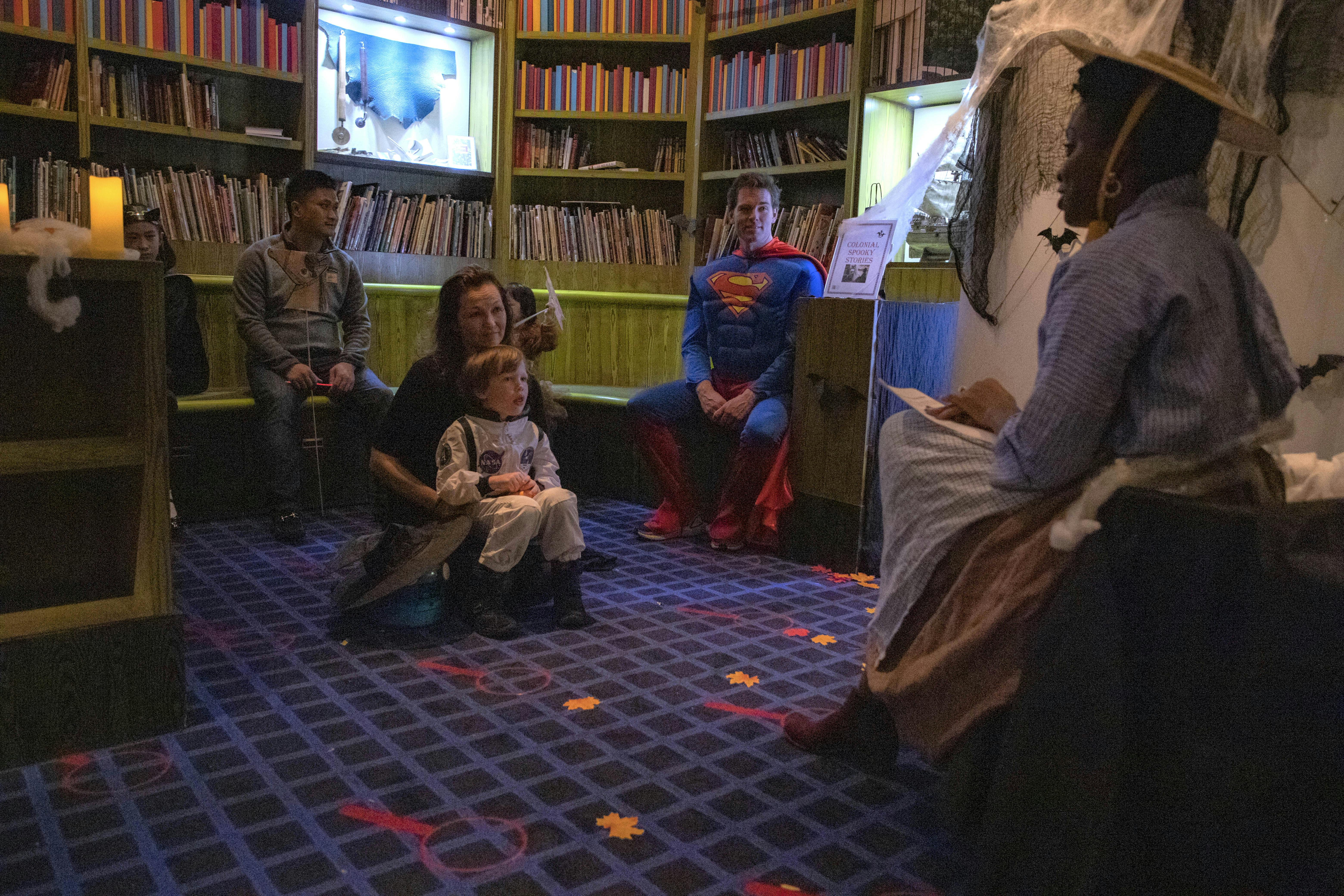 a historical interpreter reading to kids dressed in Halloween costumes in the children's museum