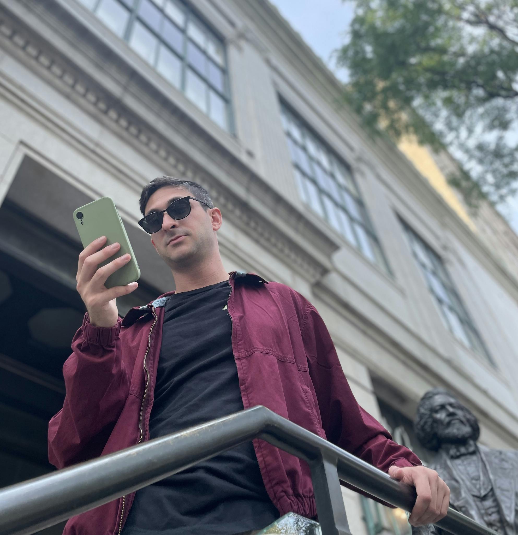 A visitor in sunglasses using a smartphone outside of New-York Historical Society