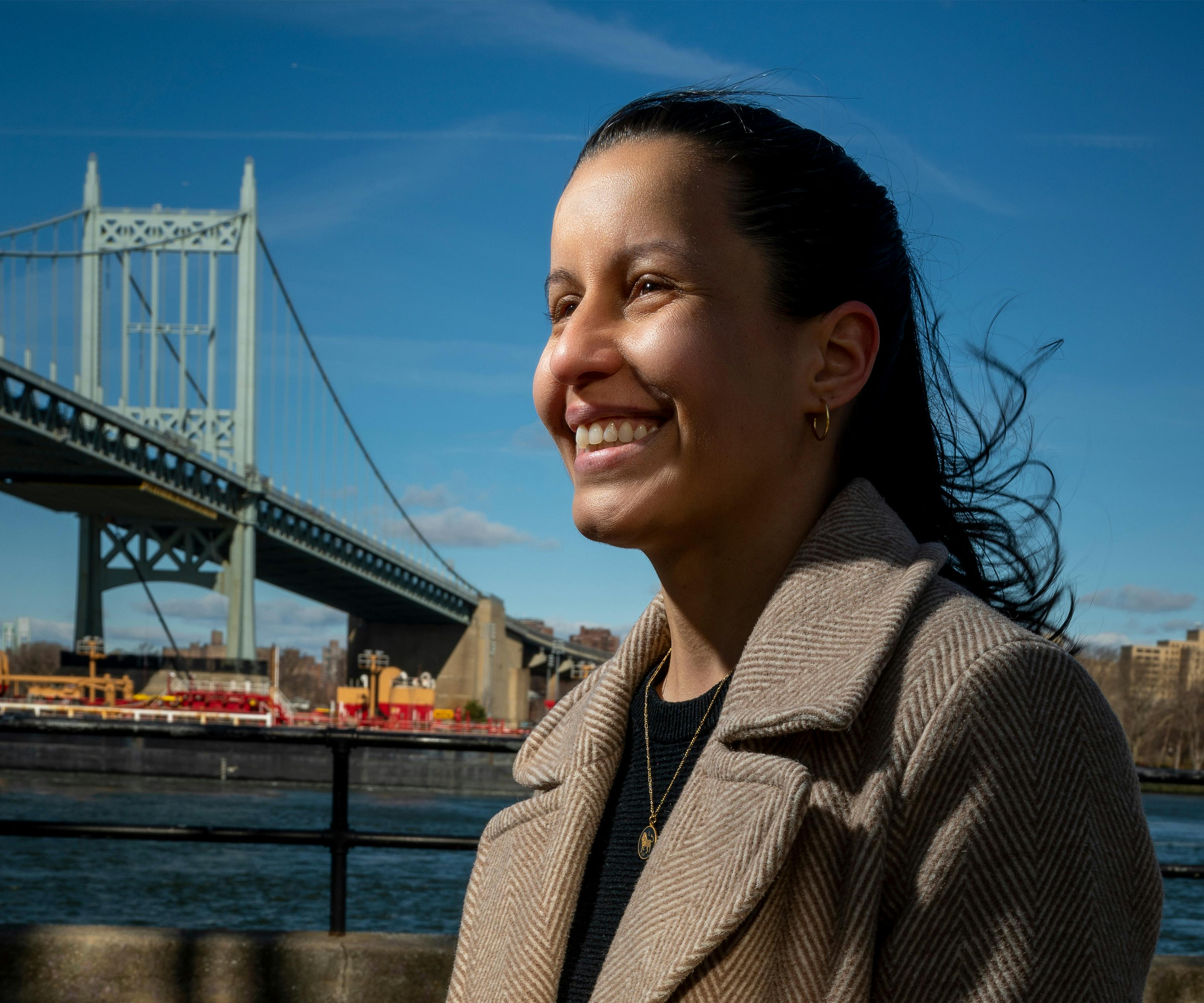 NYC council member Tiffany Cabán standing outside against the backdrop of the Queensboro bridge