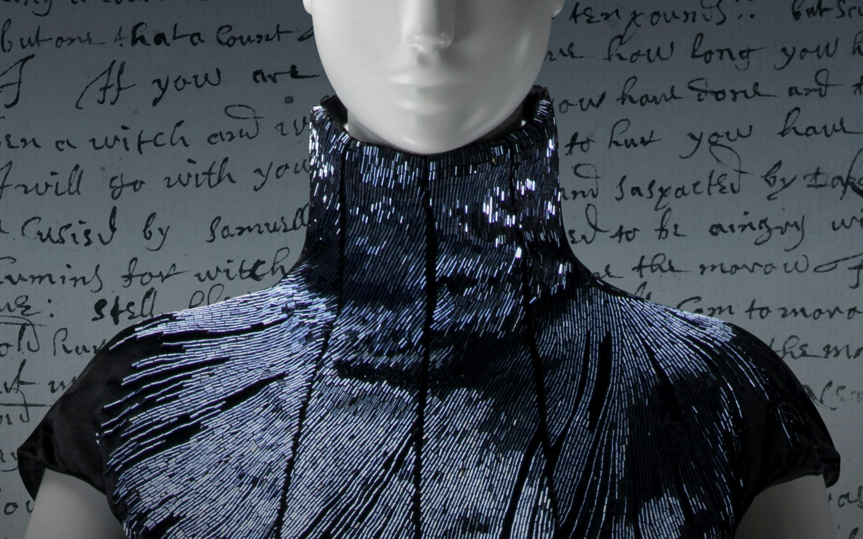A white mannequin wearing an black, shimmering alexander McQueen gown