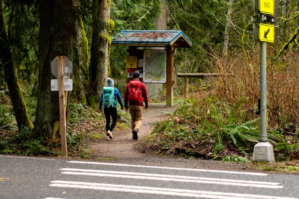 Two people starting a hike at a trailhead in their Oboz hiking shoes.