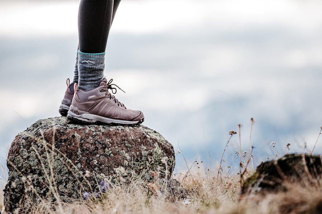 A person standing on a rock in the Oboz Sypes Mid Leather Waterproof hiking boot.