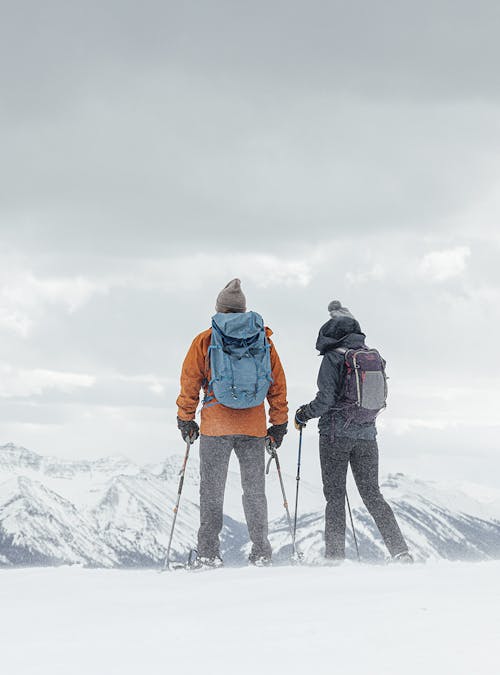 Two people on a snowy ridgeline wearing Oboz Bangtail insulated hiking boots.