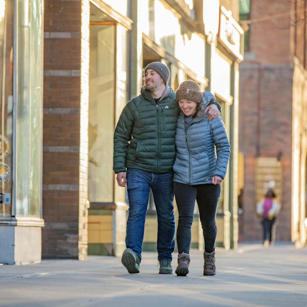 A couple walks downtown Bozeman while staying warm in puffy jackets and Oboz insulated boots.