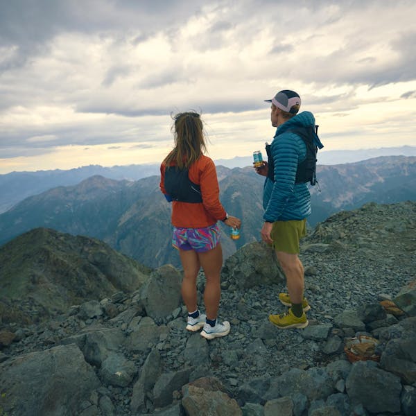 Two hikers gazing upon a mountain landscape after scaling a peak.