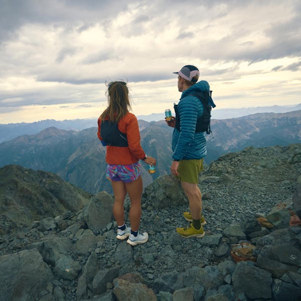 Two hikers gazing upon a mountain landscape after scaling a peak.